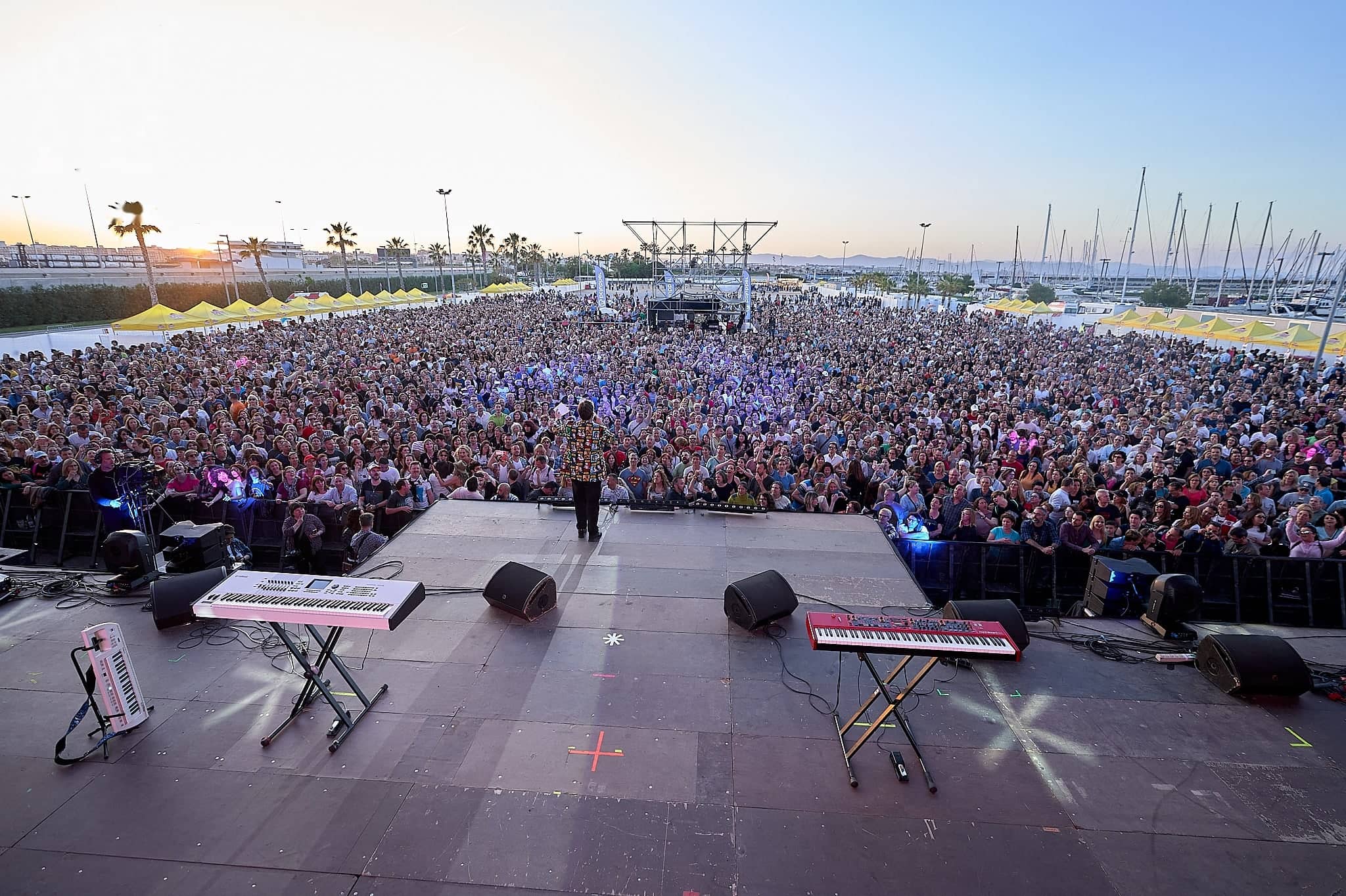 Escenario al aire libre frente a miles de personas al atardecer