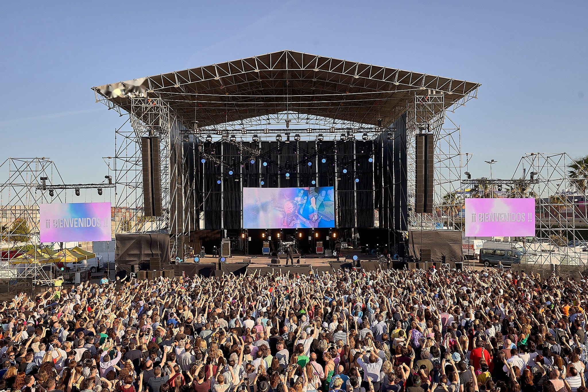 Gran escenario con pantallas y el público con las manos en alto