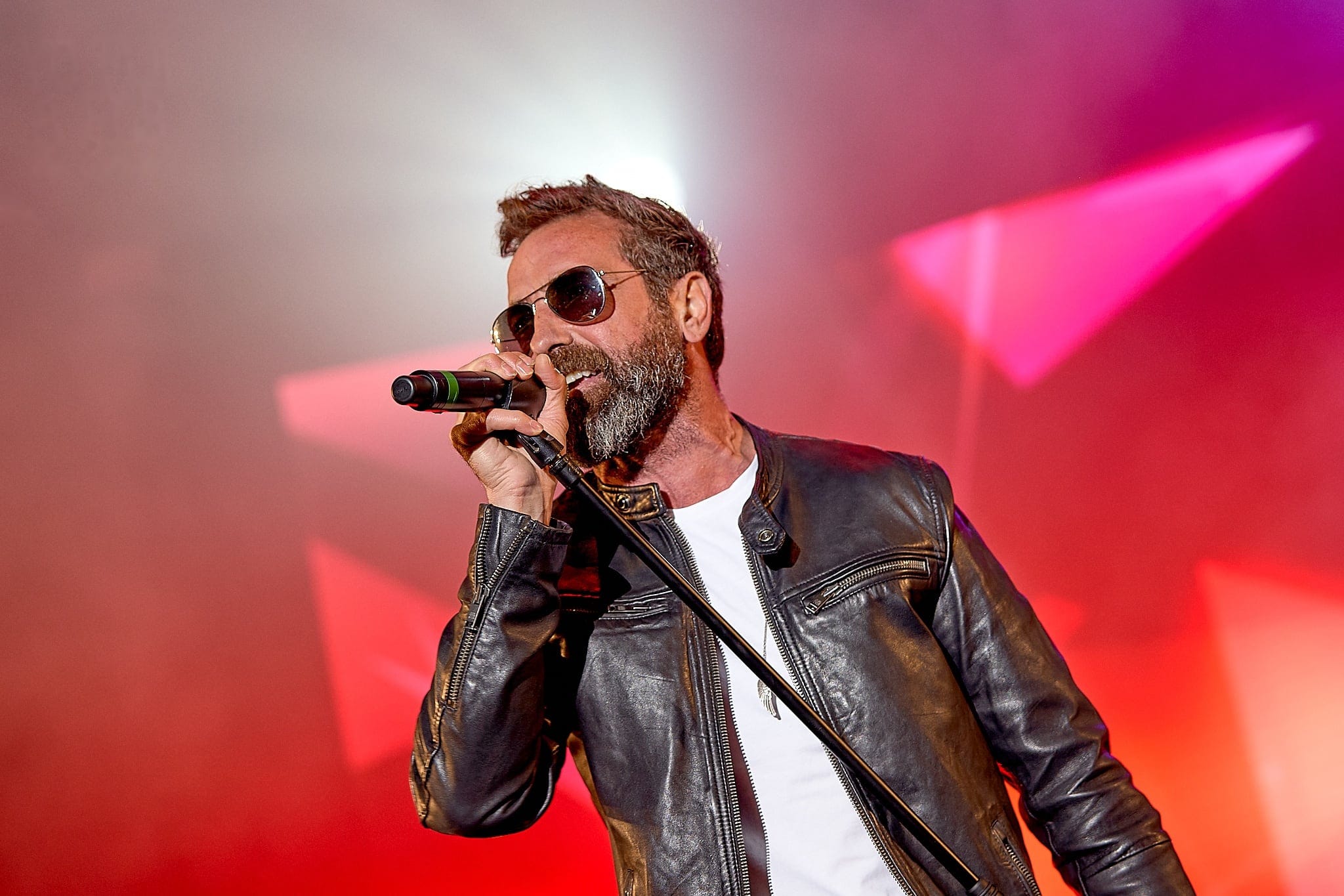 Cantante con gafas de sol y chaqueta de cuero en pleno concierto
